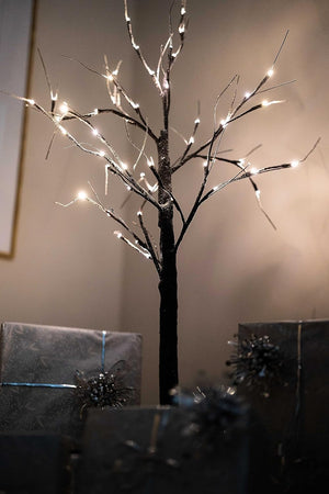 Decorative tree with lights against a plain wall
