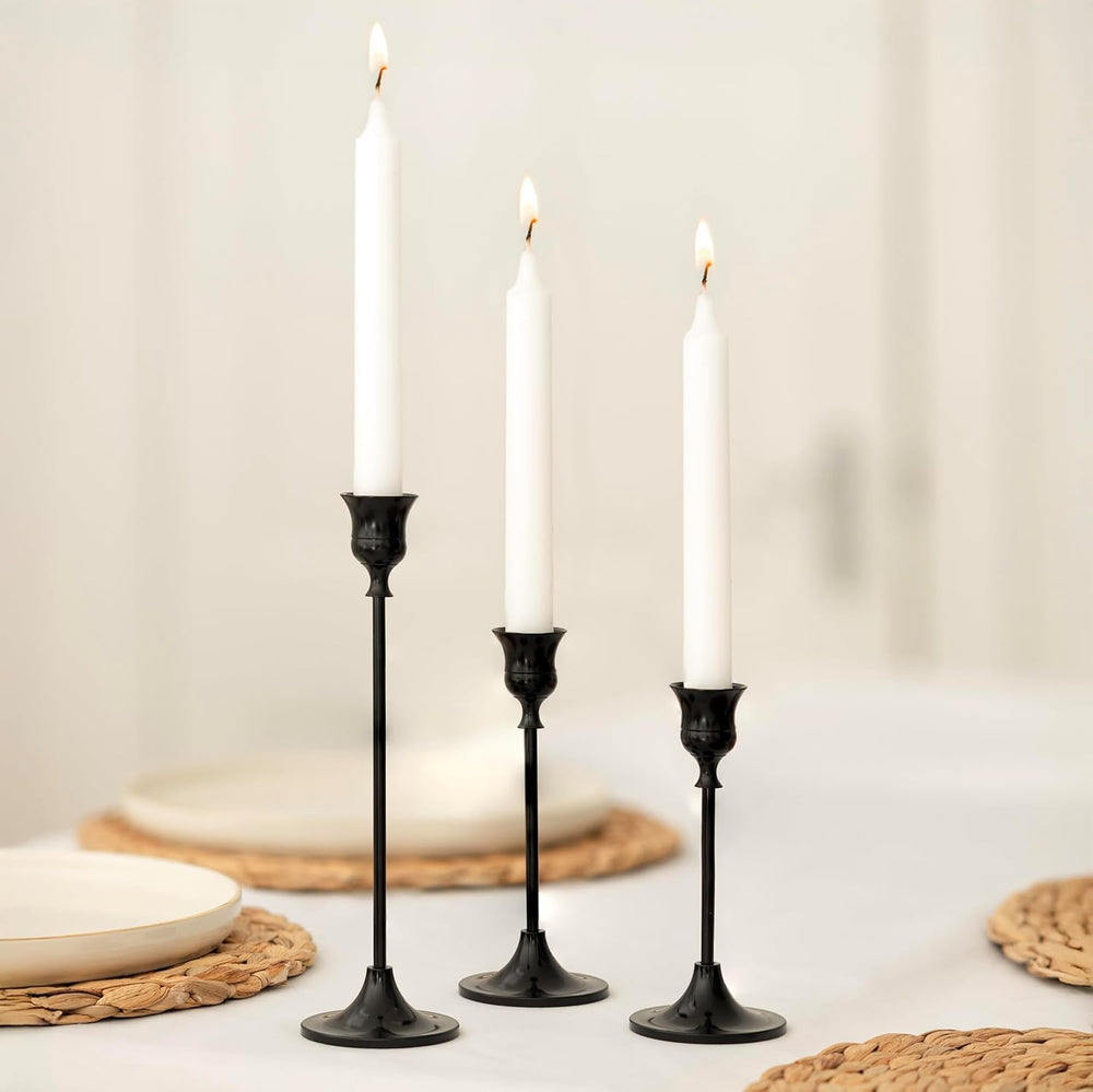 Three black candlesticks with white candles on a neutral background