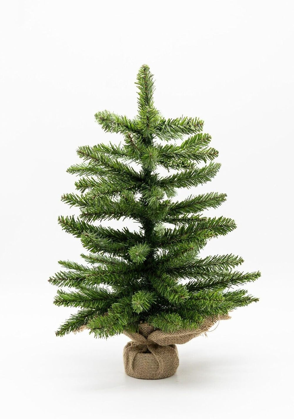 Small Christmas tree on a desk with festive decorations in the background