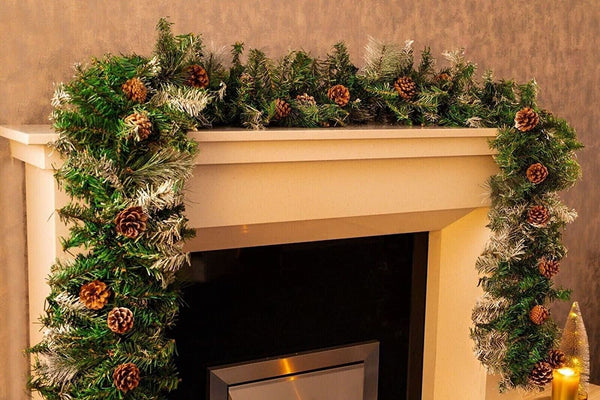 Decorative Christmas garland on a fireplace mantel with pinecones and evergreen branches.