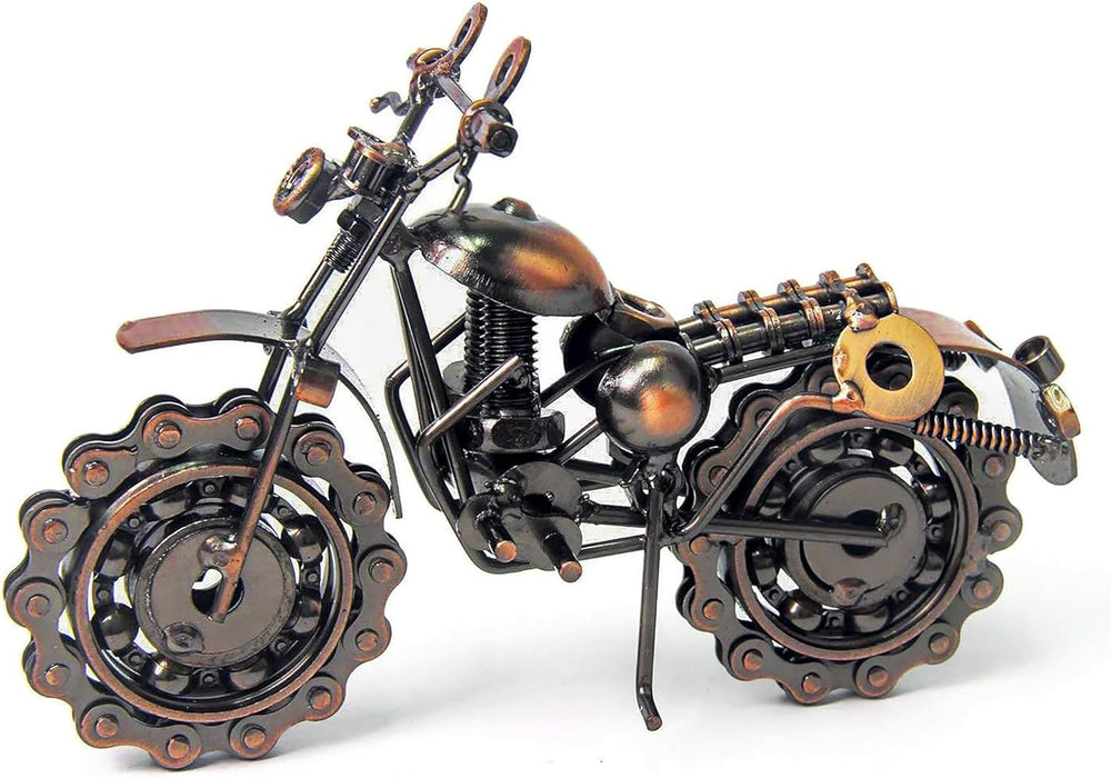 Decorative metal motorcycle sculpture on a table with a candle and vase in the background.