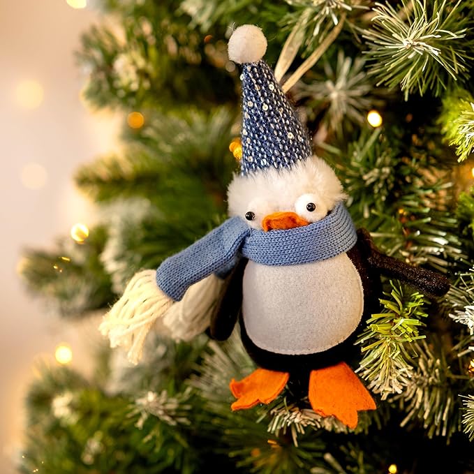 Decorative penguin ornament with a blue scarf and hat on a Christmas tree.