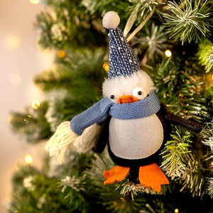 Decorative penguin ornament with a blue scarf and hat on a Christmas tree.