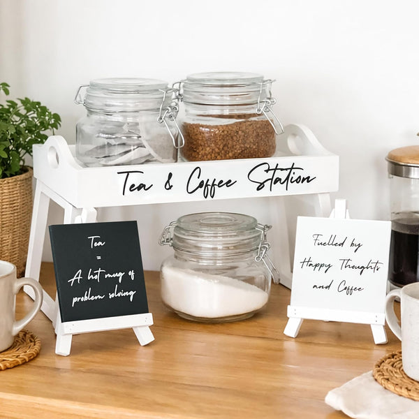 Tea and coffee station with jars and signs on a wooden surface.
