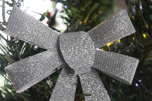 Silver glittery bow ornament on a Christmas tree