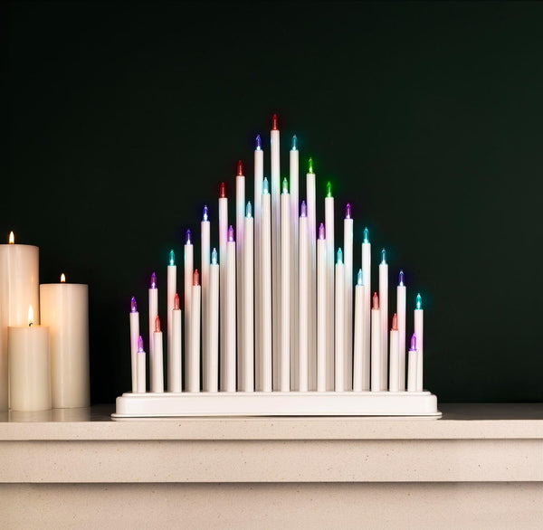 Colorful candle arrangement on a white base against a dark background