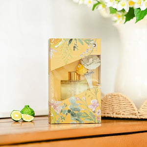 Floral-themed perfume packaging on a wooden surface with limes and flowers in the background