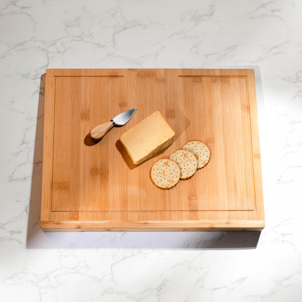 Wooden cutting board with cheese and crackers on a marble countertop