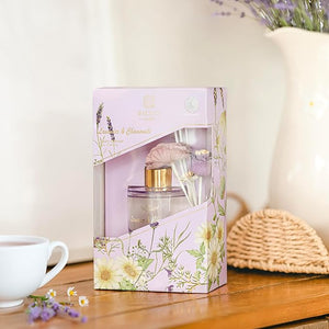 Perfume set in a decorative box on a wooden surface with a cup and flowers.
