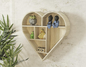 Heart-shaped wooden shelf with decorative items on a light background