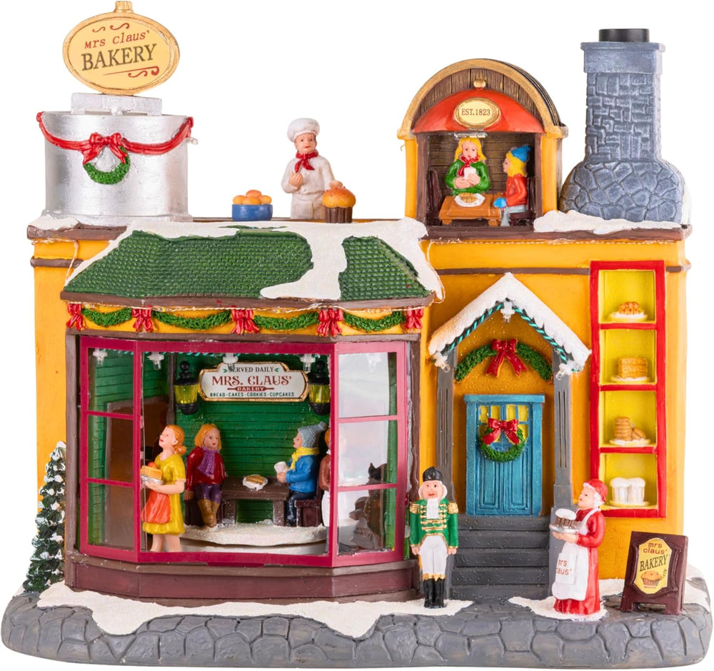 Decorative model of a bakery with animated figures and lights on a dark background