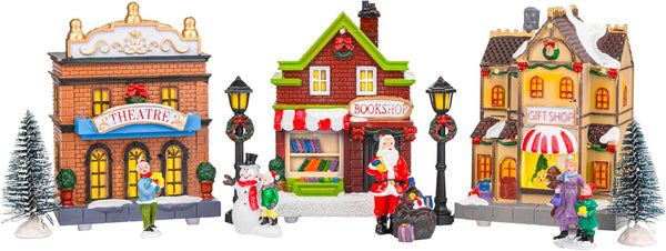 Christmas village scene with miniature buildings and figures on a white background.