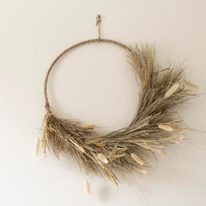 Wreath made of dried grasses and twigs on a plain background