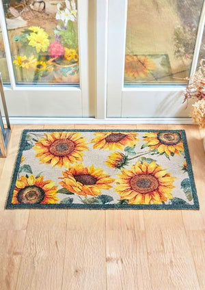 Decorative doormat with sunflower pattern on a wooden floor.