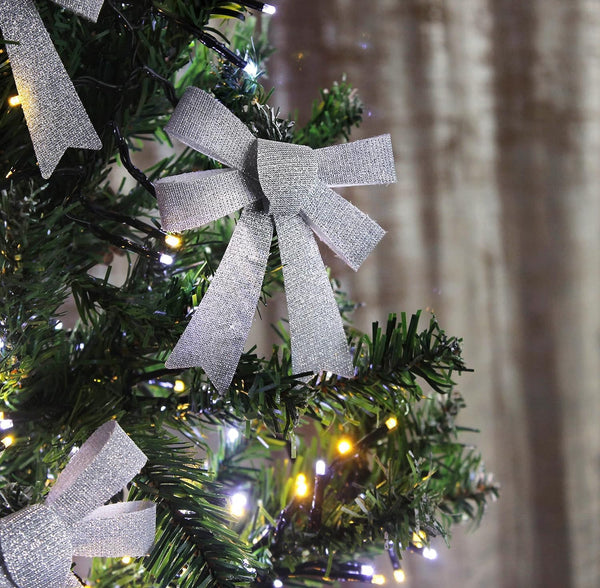 Silver glittery bows on a Christmas tree with blurred background
