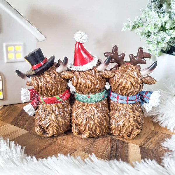 Three decorative figures of dogs wearing festive hats and scarves on a wooden surface.