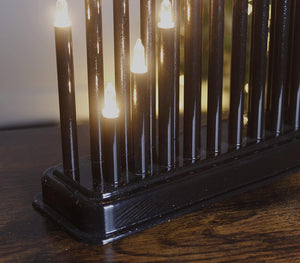 Decorative black metal fence with illuminated lights on a wooden surface