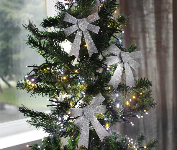 Decorated Christmas tree with silver ribbons and lights in a room setting.