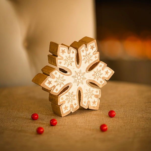 Wooden snowflake ornament with red berries on a textured surface
