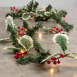 Decorative Christmas garland with green leaves and red berries on a neutral background