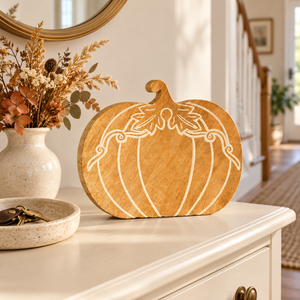 Wooden pumpkin decoration with cream detailing on a hallway console beside dried flowers and a ceramic key dish.