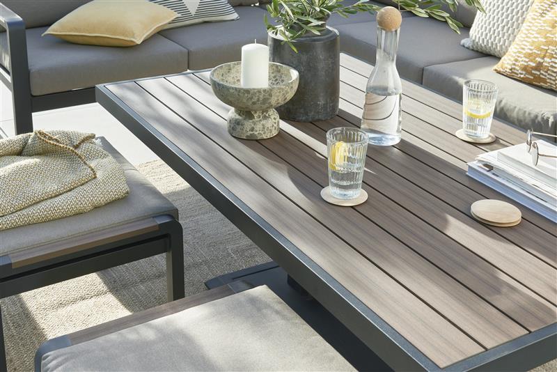 Outdoor patio set with gray sofa, table, and chairs on a tiled patio.