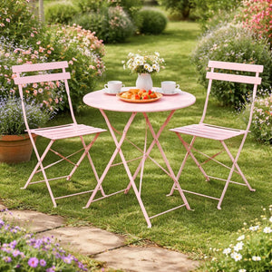 Pink metal table and chairs set on a garden with flowers and plants.