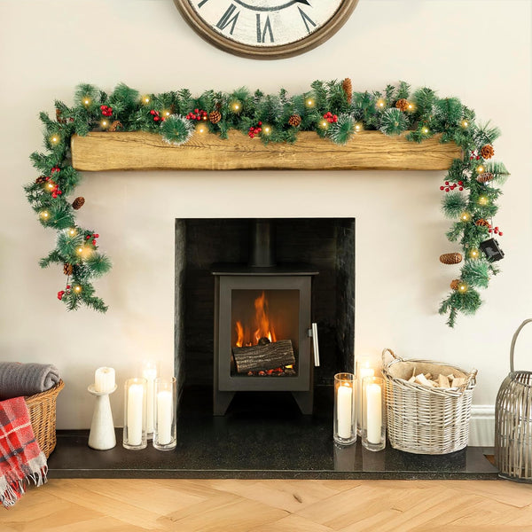 Decorated fireplace with Christmas garland, candles, and a clock on the wall.