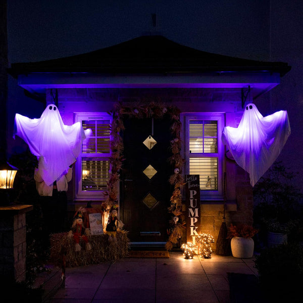 Halloween-themed outdoor decoration with ghosts, pumpkins, and lights on a house exterior.
