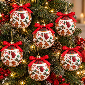 Six Christmas tree ornaments hanging on a decorated Christmas tree. The ornaments are round, white, and decorated with gingerbread men, candy canes, holly, and red stockings, each topped with a red ribbon bow.