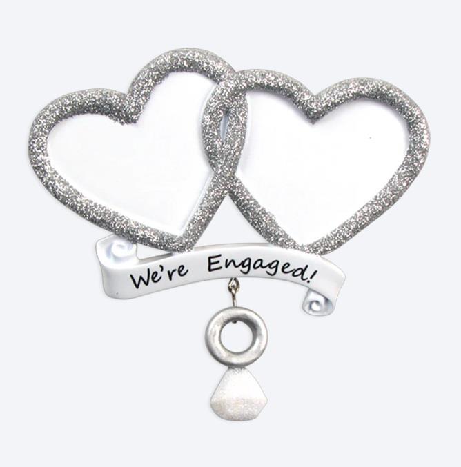 Decorative item with two interlocking hearts and a banner saying 'We're Engaged!' on a white background.