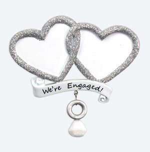 Decorative item with two interlocking hearts and a banner saying 'We're Engaged!' on a white background.