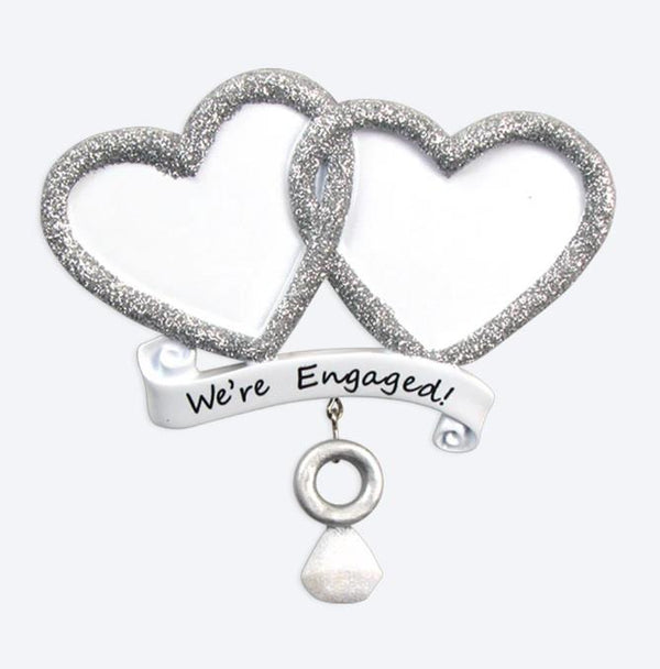 Decorative item with two interlocking hearts and a banner saying 'We're Engaged!' on a white background.