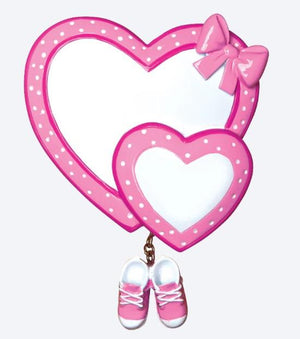 Heart-shaped frame with polka dots and a bow, featuring pink baby shoes on a white background.