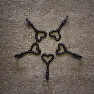 Five black heart-shaped hooks on a textured brown surface