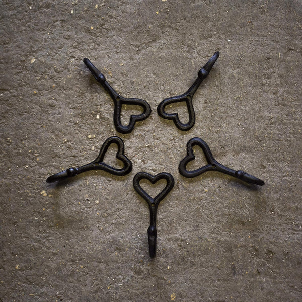 Five black heart-shaped hooks on a textured brown surface