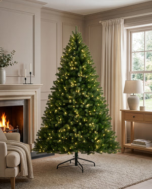 A tall artificial Christmas tree with warm white lights, displayed in a cozy living room next to a fireplace and window.