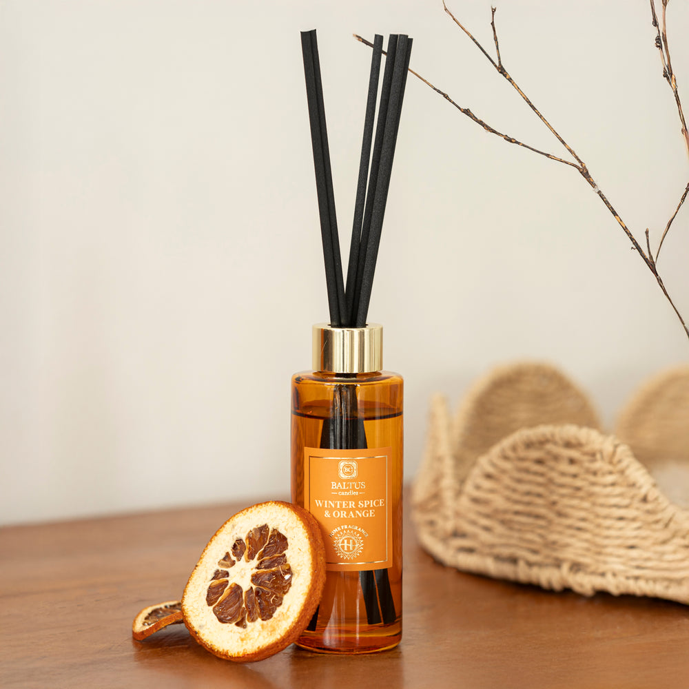 Reed diffuser with black sticks on a wooden surface with decorative elements