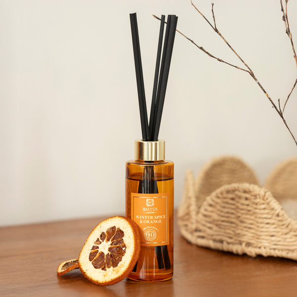 Reed diffuser with black sticks on a wooden surface with decorative elements