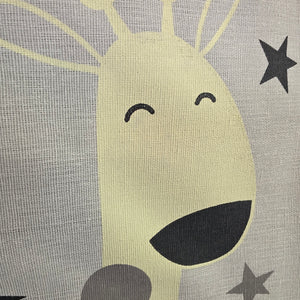 A close-up of a fabric surface featuring a stylized cartoon face with closed smiling eyes, a dark mouth, and gray stars on a light gray textured background.