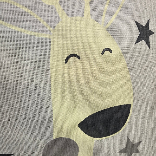 A close-up of a fabric surface featuring a stylized cartoon face with closed smiling eyes, a dark mouth, and gray stars on a light gray textured background.