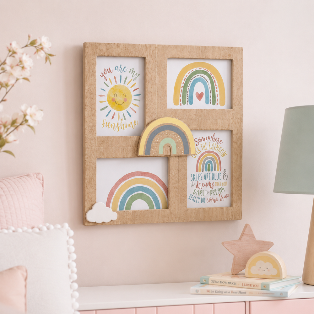 A square natural wood picture frame with four inset panels decorated with colorful children's artwork, including suns, rainbows, clouds, and inspirational quotes, displayed on a pale pink wall above a styled shelf.