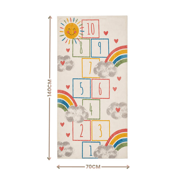 A rectangular rug or mat shown flat against a white background, with dimension arrows indicating 140 cm tall and 70 cm wide. The rug has a cream base with a playful hopscotch-style number grid, rainbow arcs, gray clouds, small red hearts, and a smiling sun.