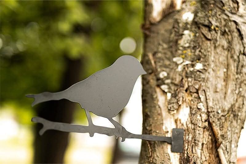 Single bird silhouette metal decoration mounted on garden tree