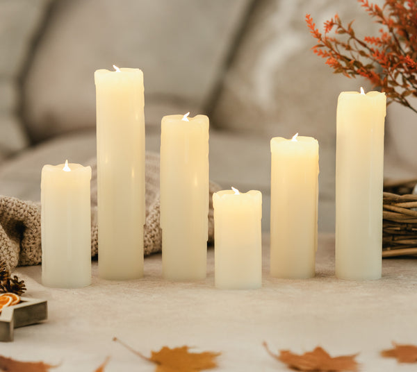 Set of six white candles on a surface with a blurred background