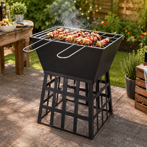 A black metal outdoor grill with a geometric frame design, shown on a stone patio in a backyard setting with food cooking on top.