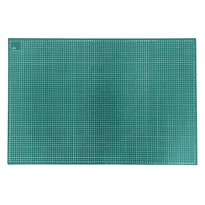 A rectangular green cutting mat with a white grid pattern and a dotted border, shown flat against a white background.