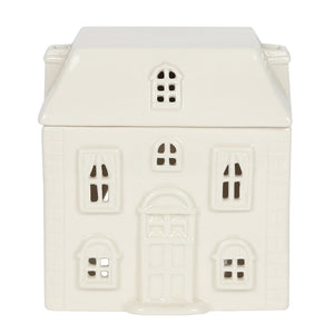 An off-white ceramic house-shaped container or ornament with detailed window cutouts and a central door, shown on a plain white background.