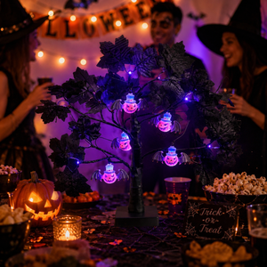 A Halloween-themed table scene with a black decorative tree lit by glowing spider-shaped bulbs. People in costume are visible in the background, along with pumpkins, popcorn, and warm string lights.