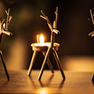 Six Christmas tea light holders arranged on a windowsill
